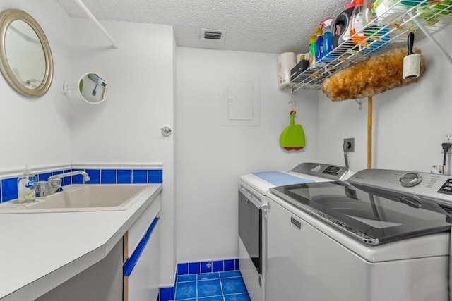 washroom featuring sink, independent washer and dryer, a textured ceiling, and dark tile patterned flooring