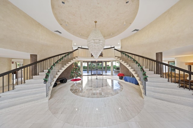 stairs with a towering ceiling and a notable chandelier