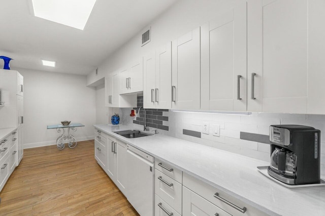 kitchen featuring white cabinetry, sink, backsplash, white dishwasher, and light hardwood / wood-style floors