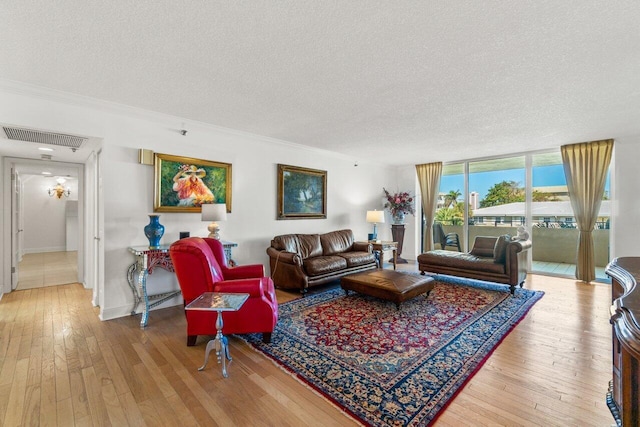 living room featuring wood-type flooring, ornamental molding, expansive windows, and a textured ceiling