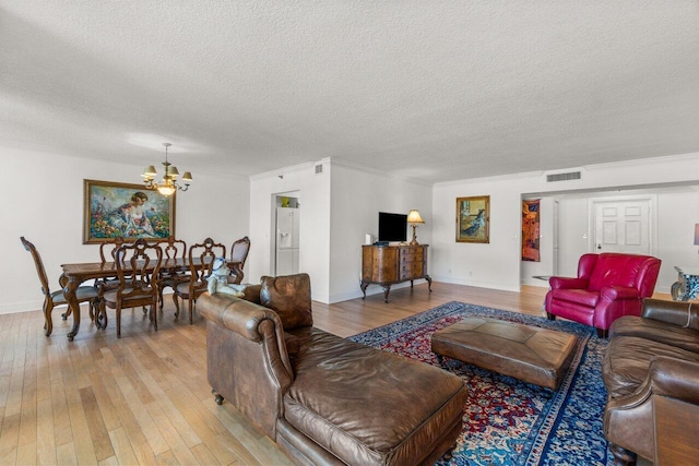 living room featuring a textured ceiling, ornamental molding, a chandelier, and hardwood / wood-style flooring