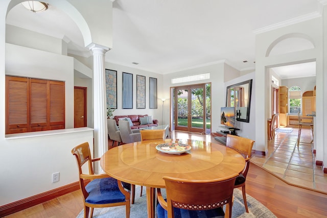 dining area featuring ornate columns, crown molding, light hardwood / wood-style floors, and a wealth of natural light