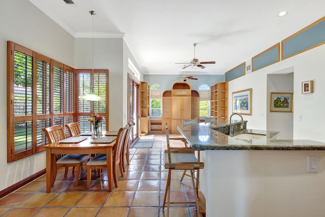 kitchen featuring a kitchen bar, sink, ornamental molding, pendant lighting, and ceiling fan