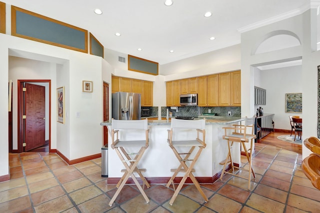 kitchen with a towering ceiling, a kitchen bar, decorative backsplash, kitchen peninsula, and stainless steel appliances