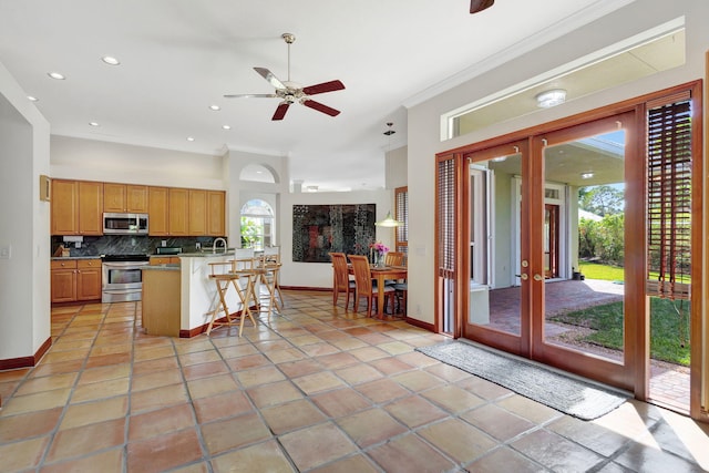 kitchen with french doors, a kitchen bar, appliances with stainless steel finishes, a wealth of natural light, and decorative backsplash