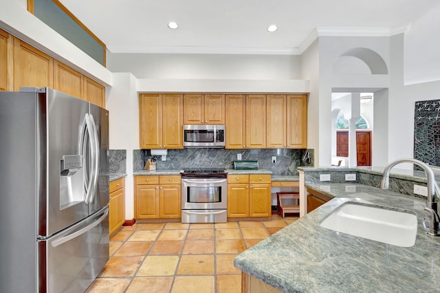 kitchen with sink, crown molding, appliances with stainless steel finishes, tasteful backsplash, and light stone counters