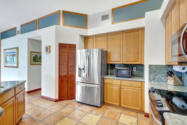 kitchen with light stone counters, backsplash, stainless steel appliances, and light tile patterned flooring