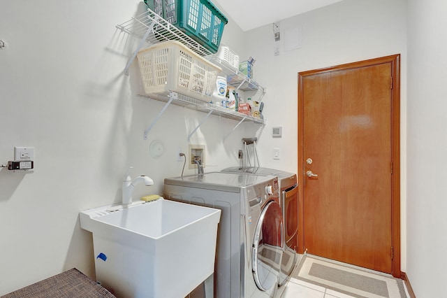 washroom featuring sink, light tile patterned floors, and washing machine and clothes dryer