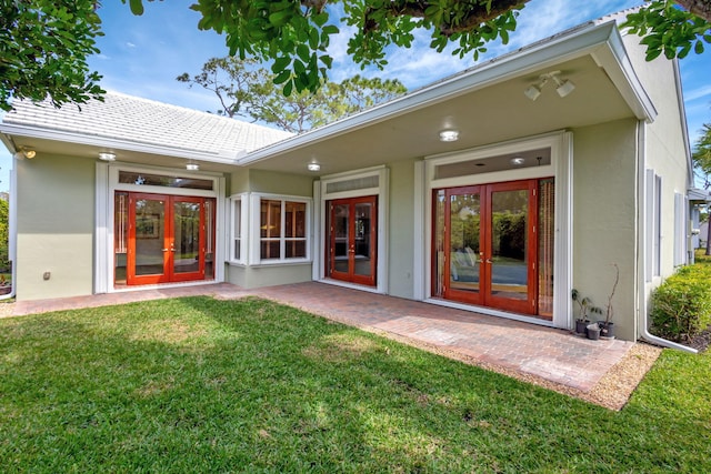 rear view of property featuring a patio, a lawn, and french doors