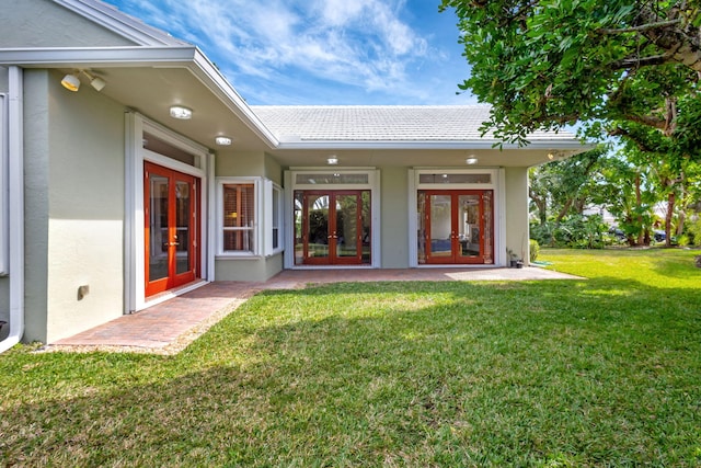 entrance to property with french doors, a yard, and a patio area