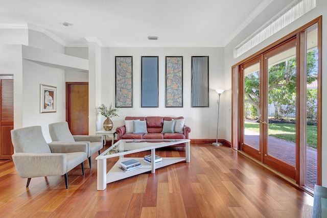 living room with crown molding, french doors, and light wood-type flooring