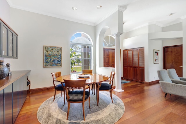 dining room with crown molding, light hardwood / wood-style flooring, and decorative columns