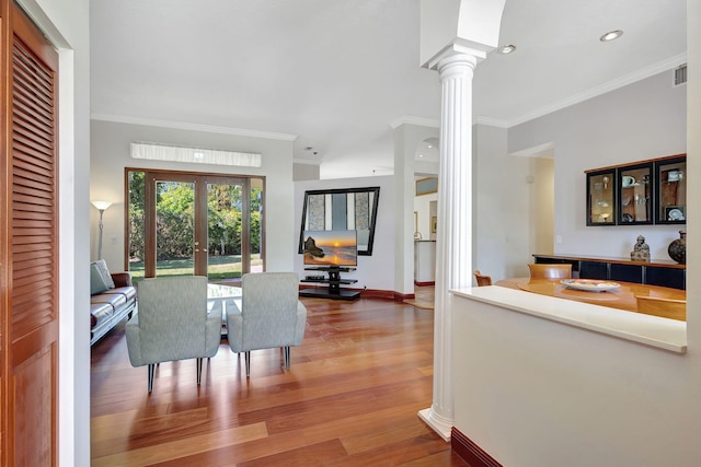 dining room featuring hardwood / wood-style flooring, crown molding, decorative columns, and french doors