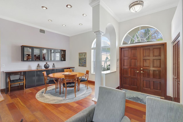 dining area with ornamental molding, wood-type flooring, and decorative columns