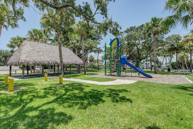 surrounding community with a lawn, a playground, and a water view