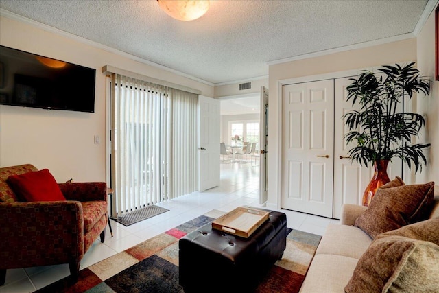 living room with light tile patterned floors, visible vents, ornamental molding, and a textured ceiling