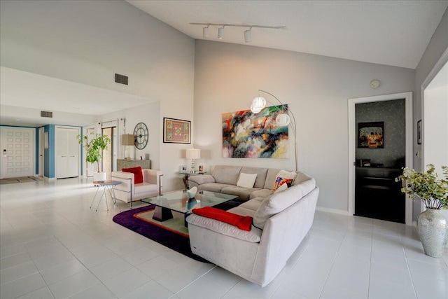 living room with high vaulted ceiling, rail lighting, visible vents, and light tile patterned floors