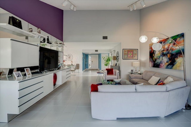 tiled living room featuring visible vents, rail lighting, and a towering ceiling