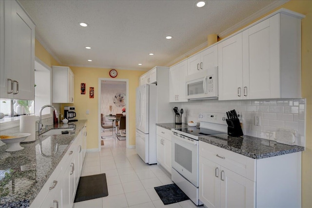 kitchen with backsplash, white cabinetry, a sink, light tile patterned flooring, and white appliances