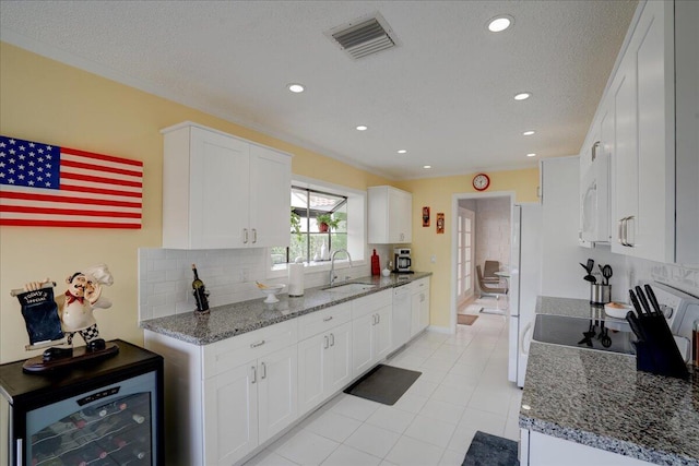 kitchen with beverage cooler, white appliances, a sink, visible vents, and tasteful backsplash