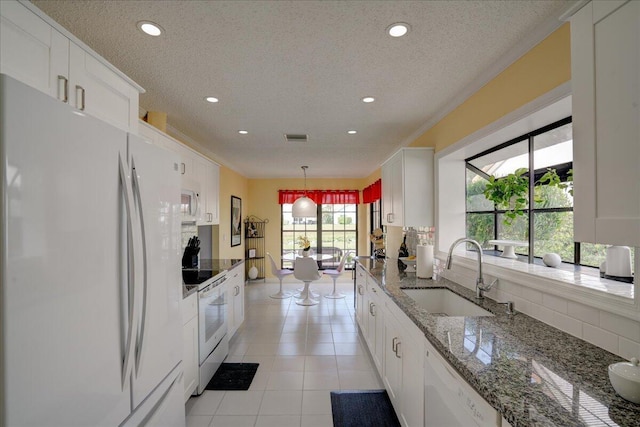 kitchen with white appliances, recessed lighting, a sink, and white cabinets