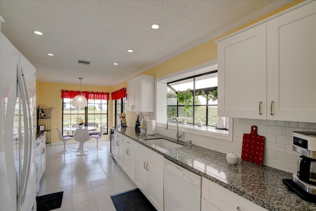 kitchen featuring white appliances, backsplash, a sink, and white cabinets