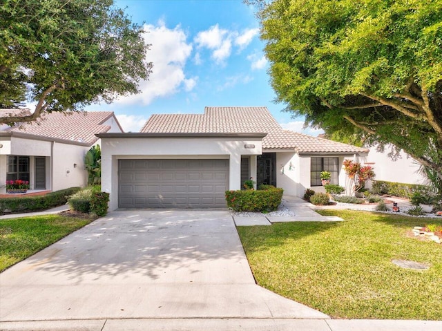 view of front of home featuring a garage, driveway, a tile roof, a front yard, and stucco siding