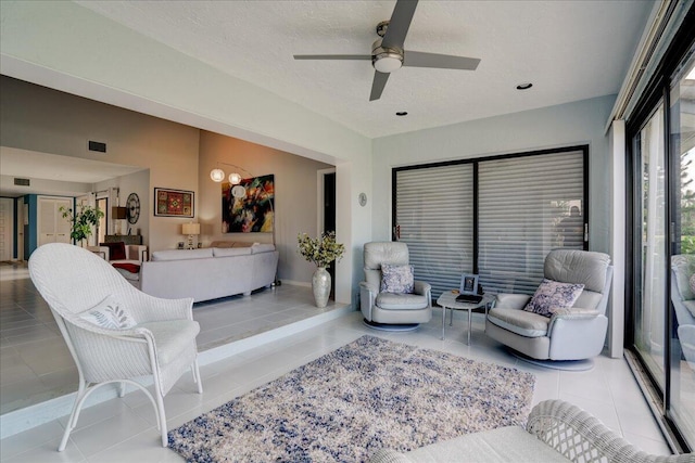 living room with a ceiling fan, visible vents, a textured ceiling, and tile patterned floors