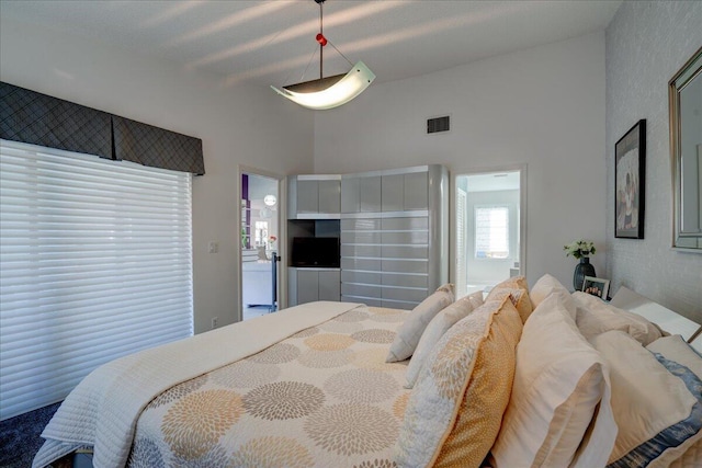 bedroom featuring high vaulted ceiling and visible vents