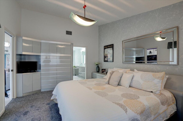 bedroom featuring lofted ceiling, ensuite bath, carpet, and visible vents