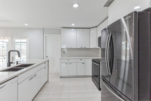 kitchen featuring white cabinets, dishwasher, black range with electric cooktop, sink, and stainless steel refrigerator