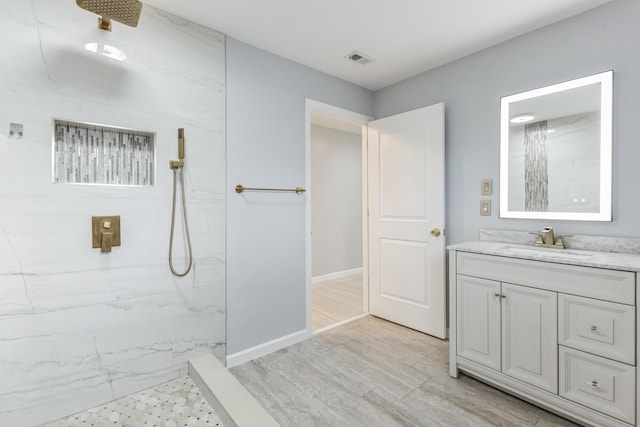 bathroom featuring wood-type flooring, tiled shower, and vanity