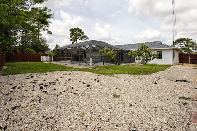 rear view of house with a swimming pool, glass enclosure, a patio area, and a yard