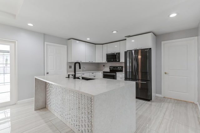 kitchen featuring a kitchen island with sink, sink, stainless steel appliances, and white cabinetry