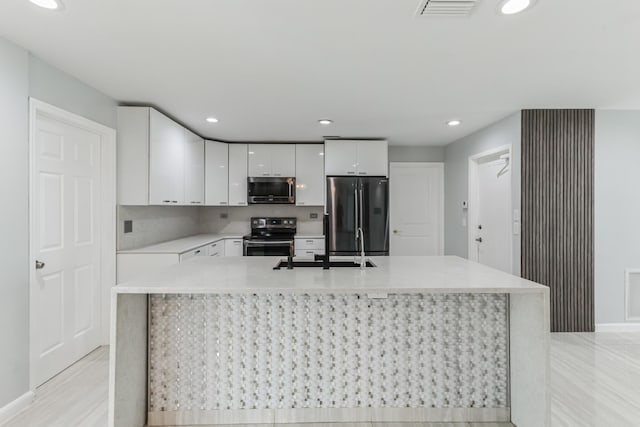 kitchen with appliances with stainless steel finishes, an island with sink, and white cabinetry