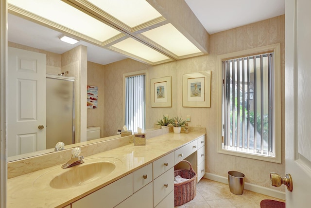 bathroom featuring tile patterned floors, toilet, a stall shower, baseboards, and vanity