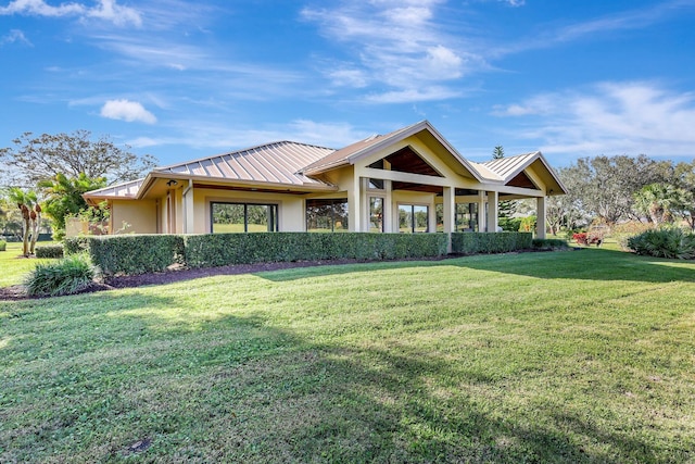 view of front of property featuring a standing seam roof, a front yard, metal roof, and stucco siding