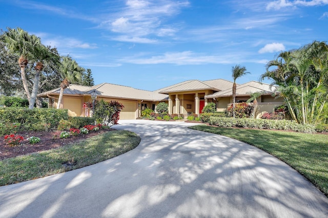 view of front of property featuring an attached garage, stucco siding, concrete driveway, a front lawn, and metal roof