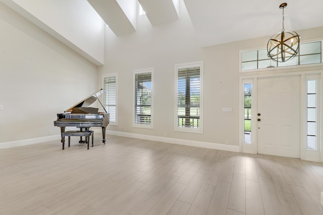 foyer entrance featuring a chandelier, a towering ceiling, and light hardwood / wood-style floors