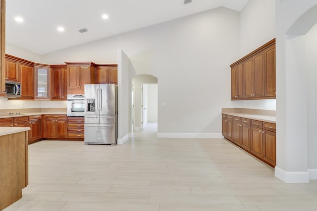 kitchen featuring appliances with stainless steel finishes, light hardwood / wood-style floors, and high vaulted ceiling