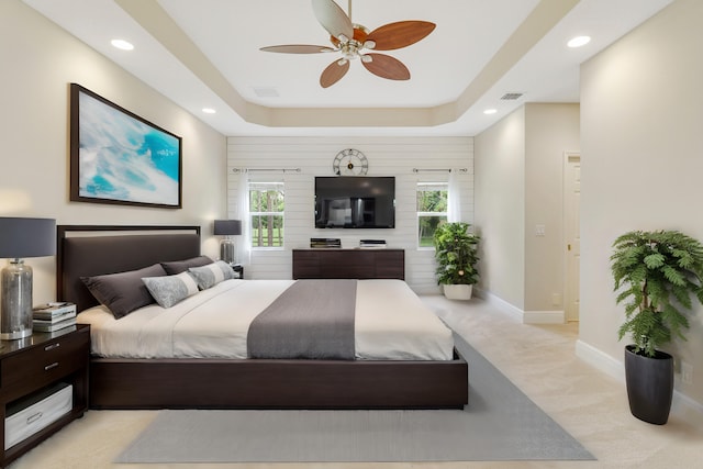 carpeted bedroom with ceiling fan and a tray ceiling