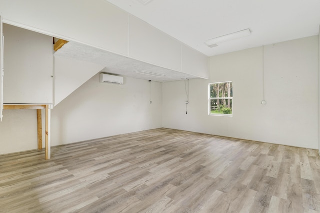 basement with an AC wall unit and light hardwood / wood-style flooring