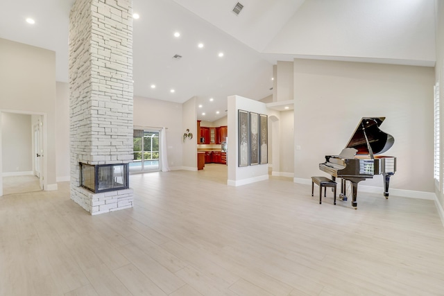 living room featuring a fireplace, high vaulted ceiling, and light wood-type flooring