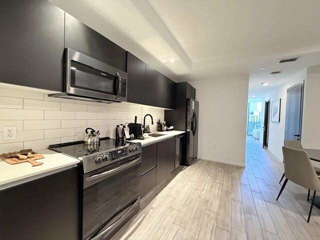 398 NE 5th St Unit 1715, Miami, FL 33132 - kitchen with backsplash, sink, light wood-type flooring, and appliances with stainless steel finishes