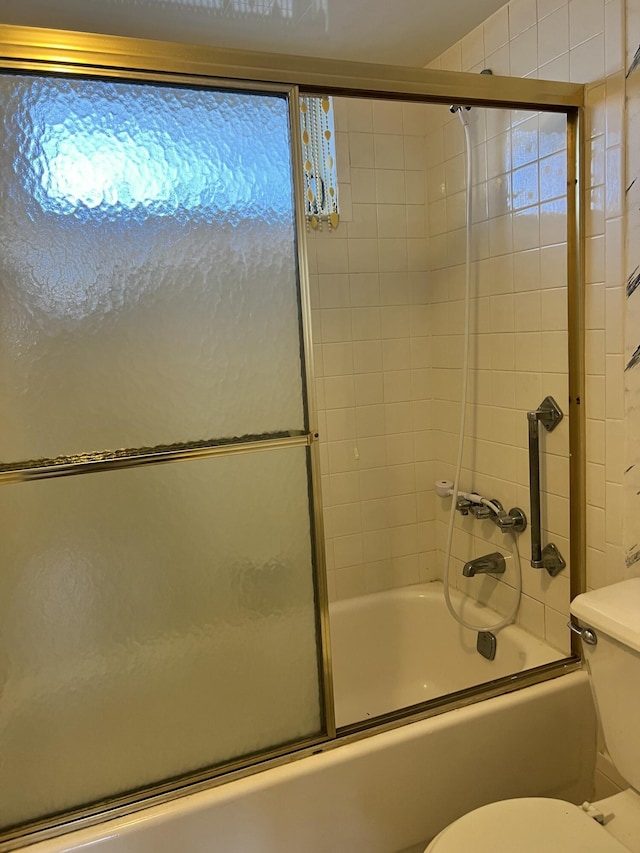 bathroom with combined bath / shower with glass door and toilet