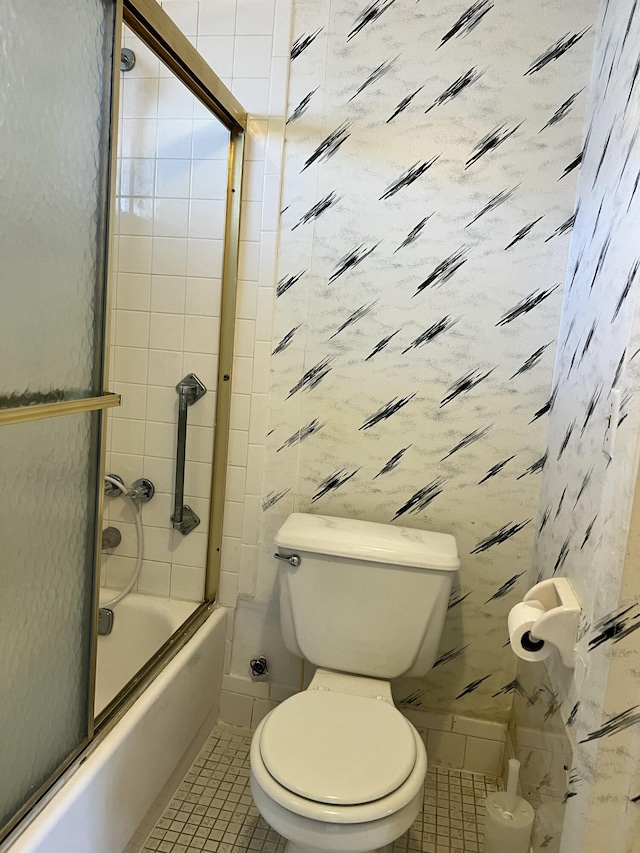 bathroom featuring tile patterned floors, toilet, and enclosed tub / shower combo