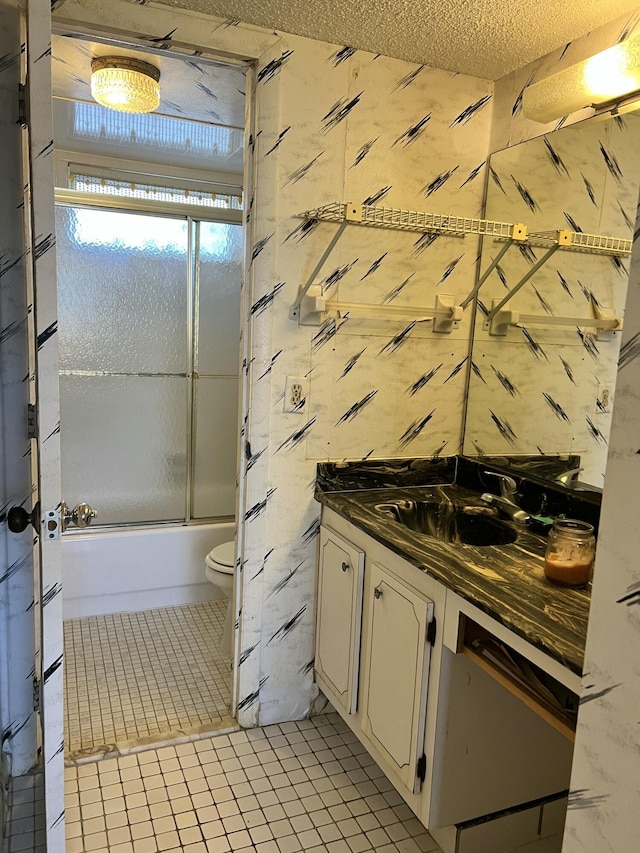 full bathroom with vanity, shower / bath combination with glass door, tile patterned flooring, toilet, and a textured ceiling