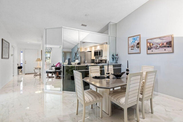 dining room with a textured ceiling and vaulted ceiling