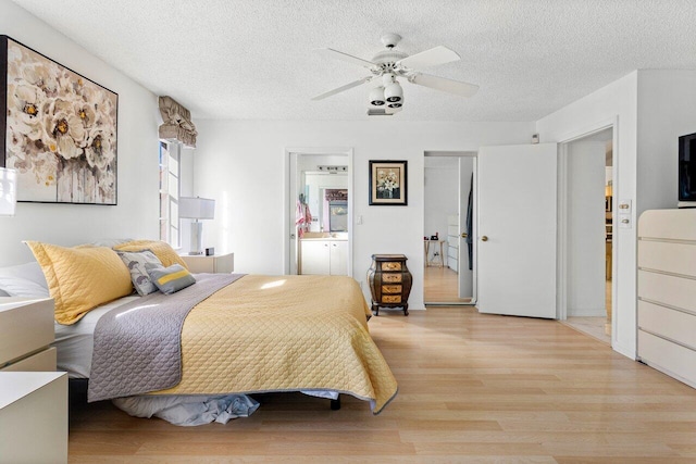 bedroom featuring ceiling fan, light hardwood / wood-style floors, a textured ceiling, and connected bathroom