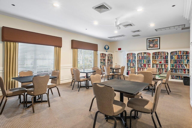 dining room with ceiling fan and light carpet